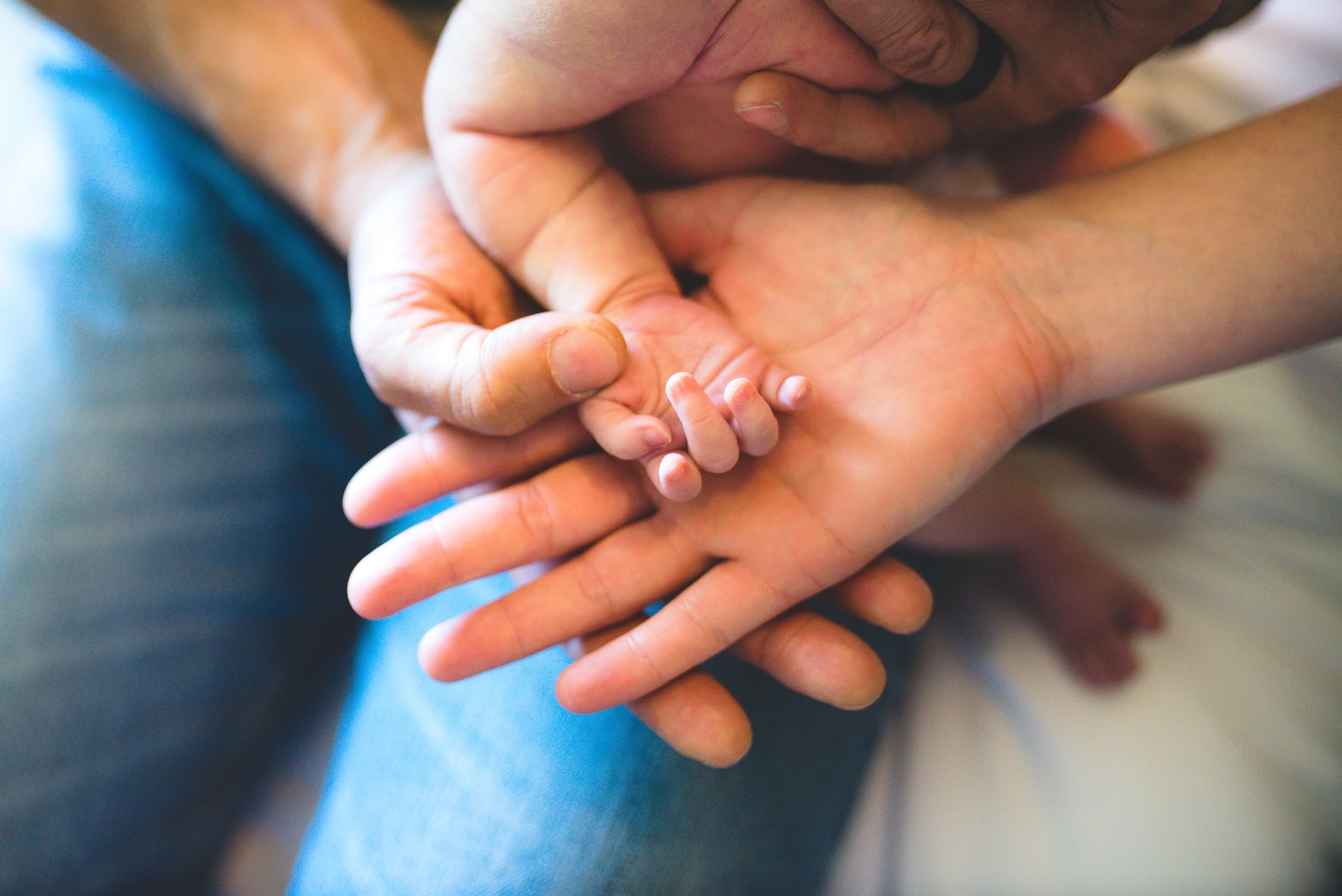 Close-up of a newborn’s tiny hand resting in the hands of both parents, symbolizing love, trust, and the journey of waiting for a miracle baby.